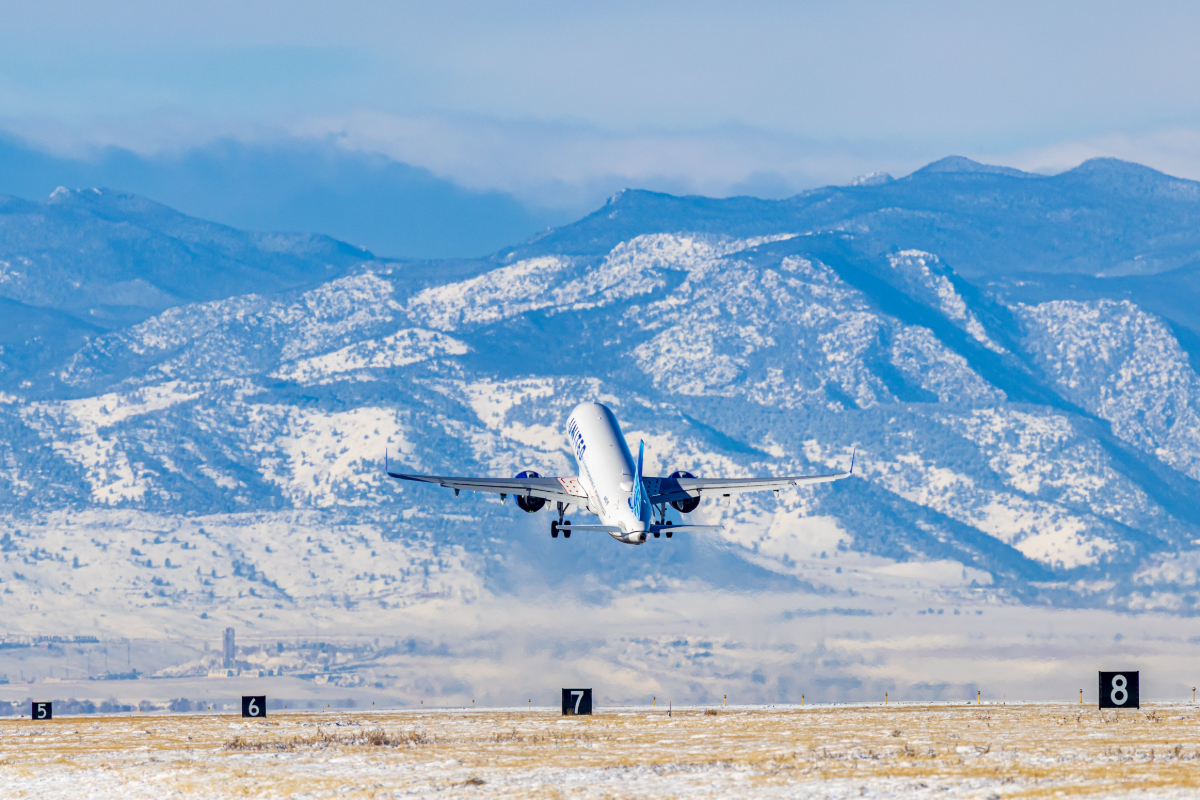 United Airlines flight takes off from Denver airport in front of snow-covered Rocky Mountains
