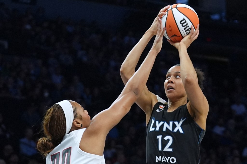 Nia Coffey holds the basketball above her head as another player tries to intercept.