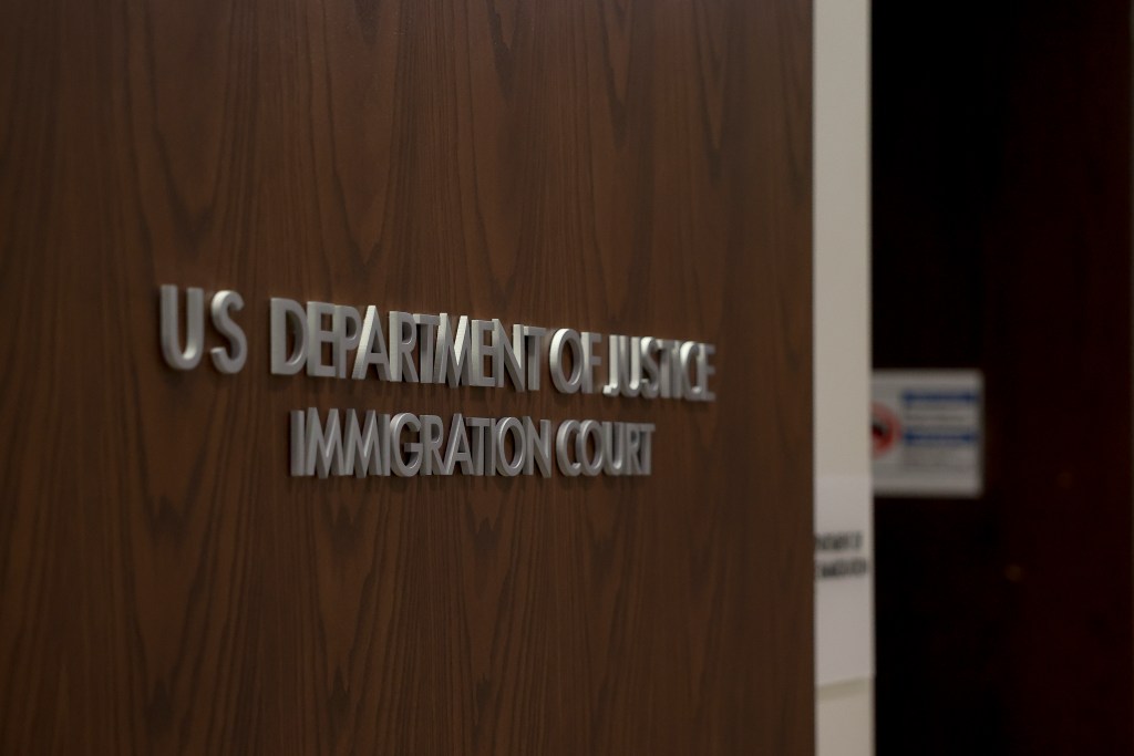 silver text on a wooden door reads us department of justice immigration court