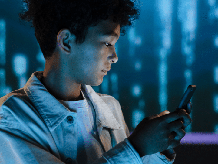 Social media: Side view of teenage boy using phone against a digital tech backdrop