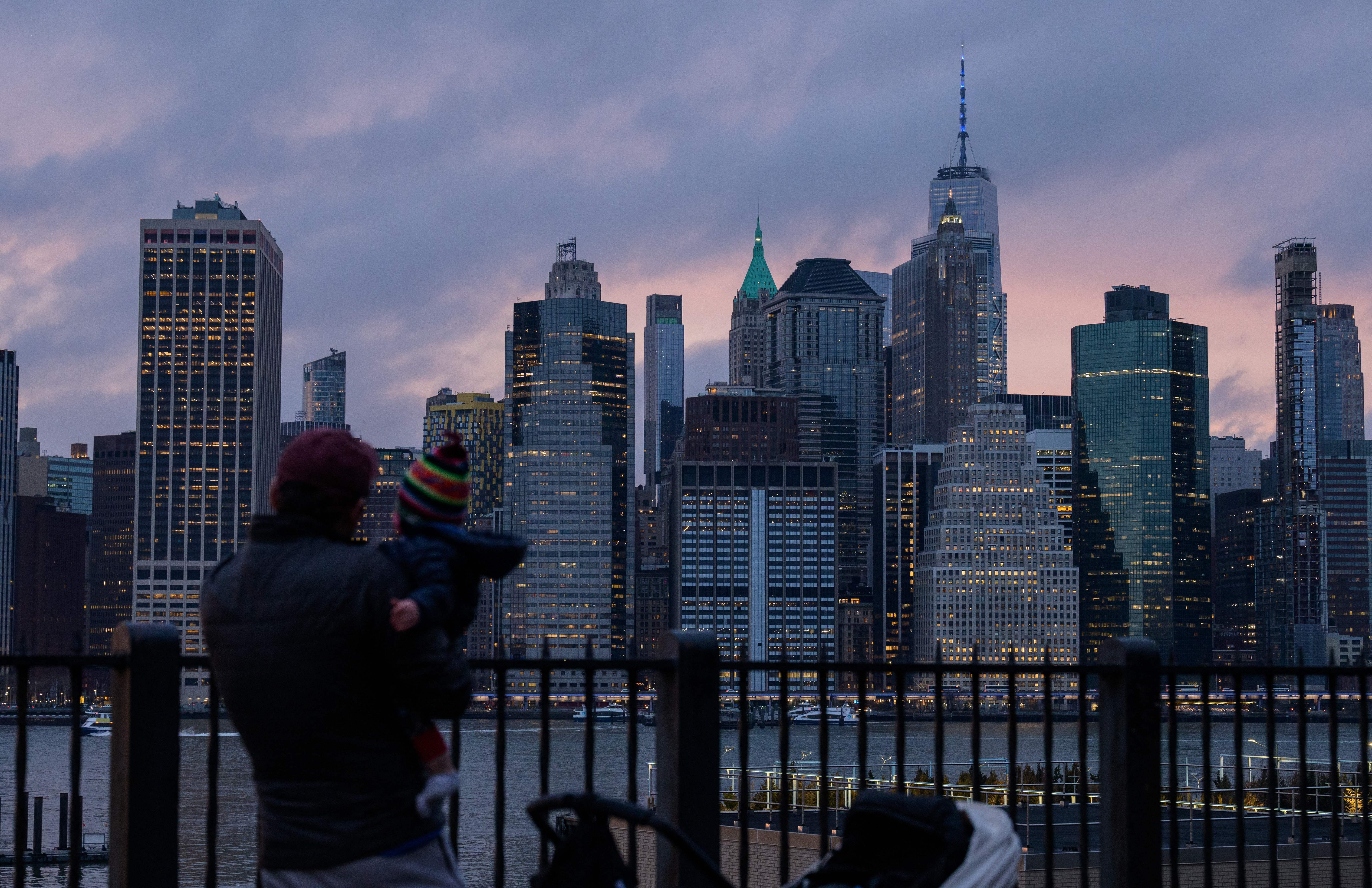 A father and child look over the skyline of lower Manhattan during sunset on January 5, 2022, in New York City.