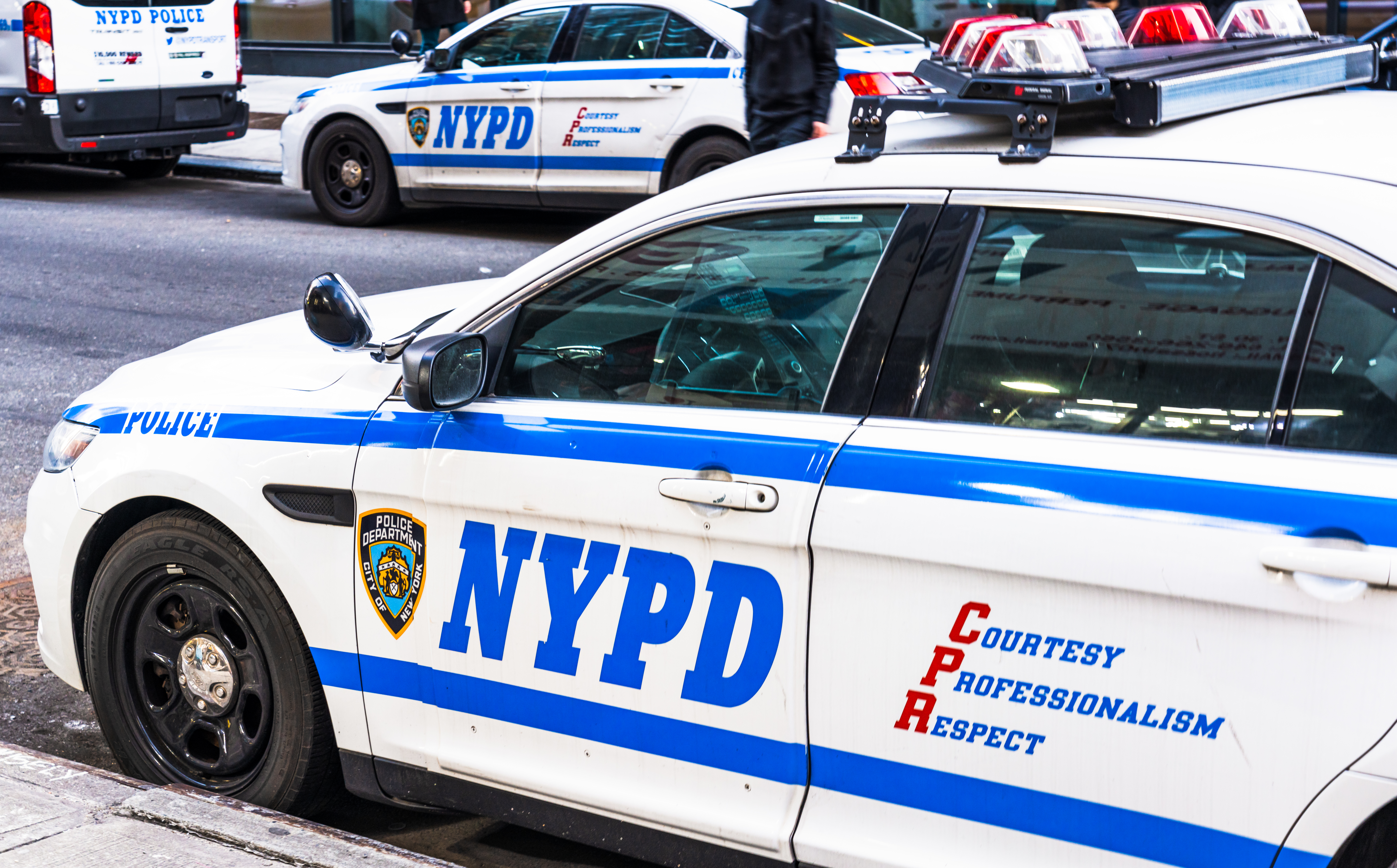 NYPD police cars and a police van on both sides of the street in Manhattan.