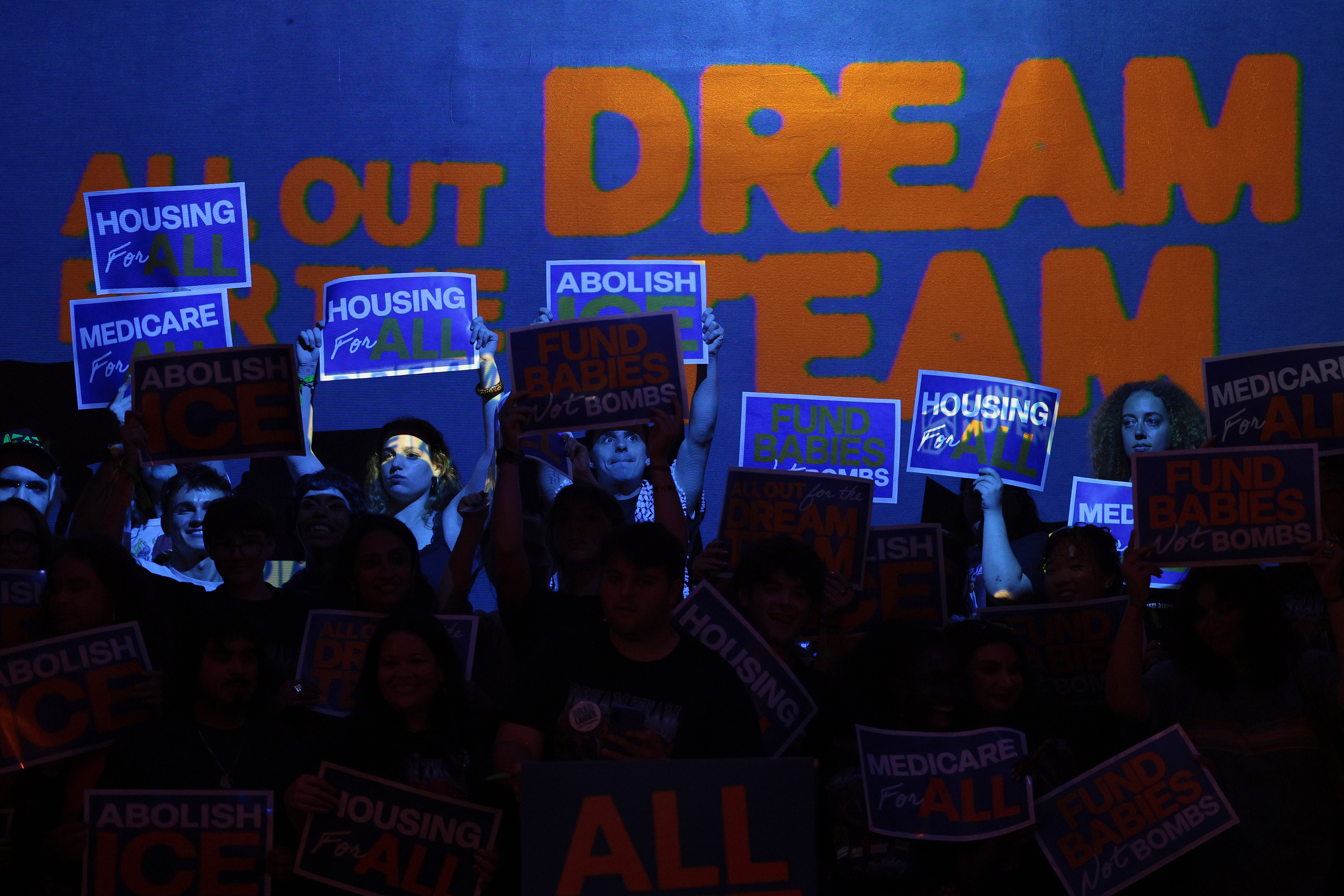 People hold signs during an election eve rally at Silo on June 22, 2026 in East Williamsburg