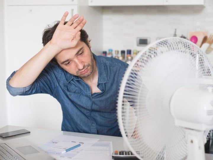 A person looking hot while working, with a fan on the desk Heat Strike
