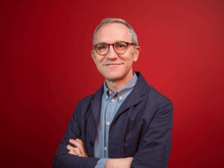 A professional portrait of James Purnell, with his arms folded against a red background. Andy Burnham has appointed him as chief of staff.