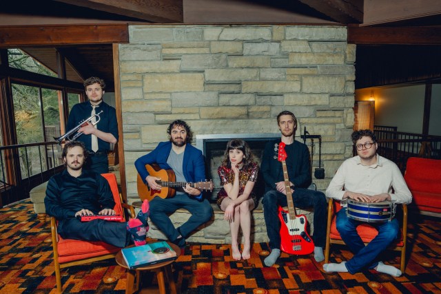 A group of people with instruments in front of a fire place.