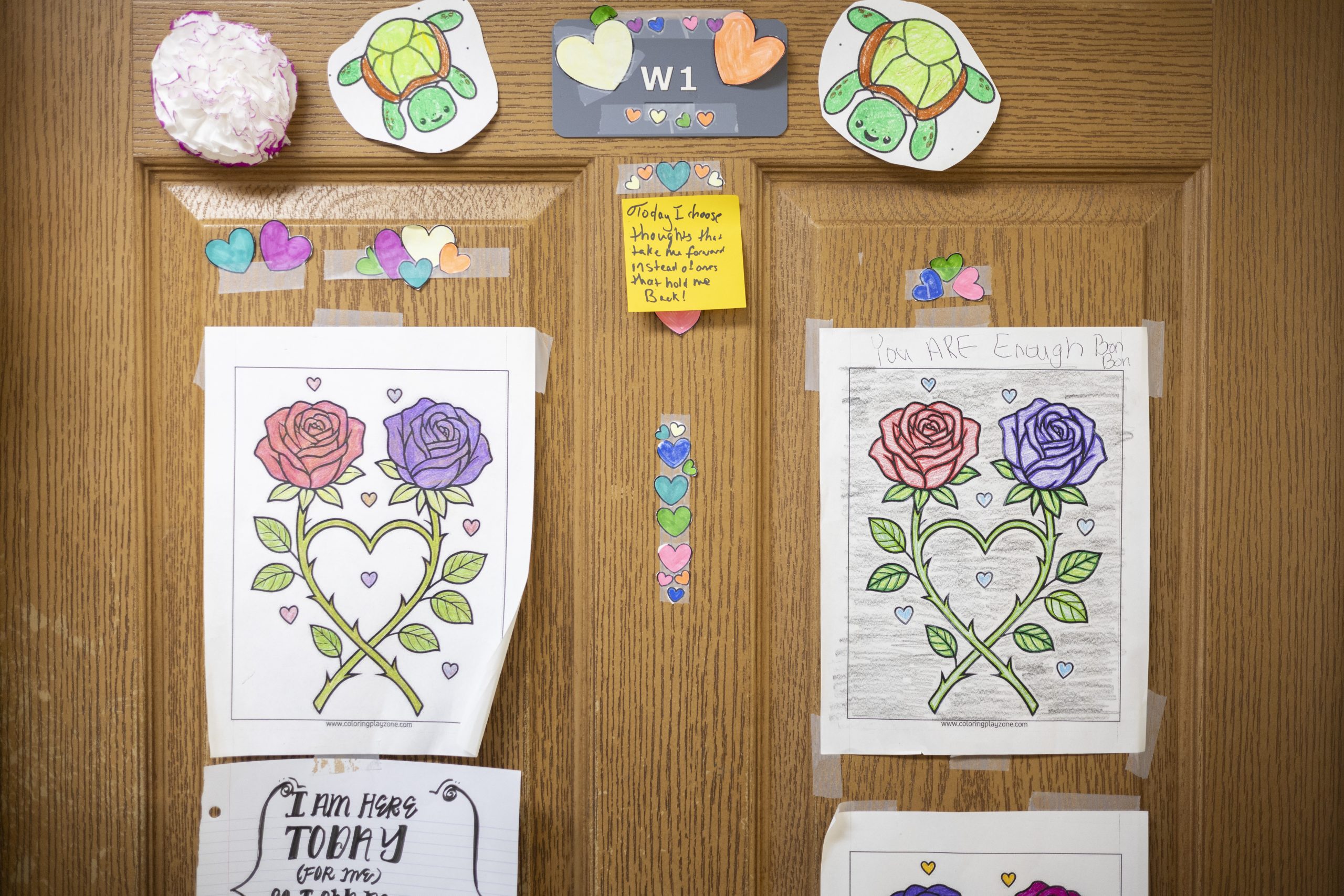 A photo of colored pencil drawings on the door of a client's room with inspirational notes about recovery.