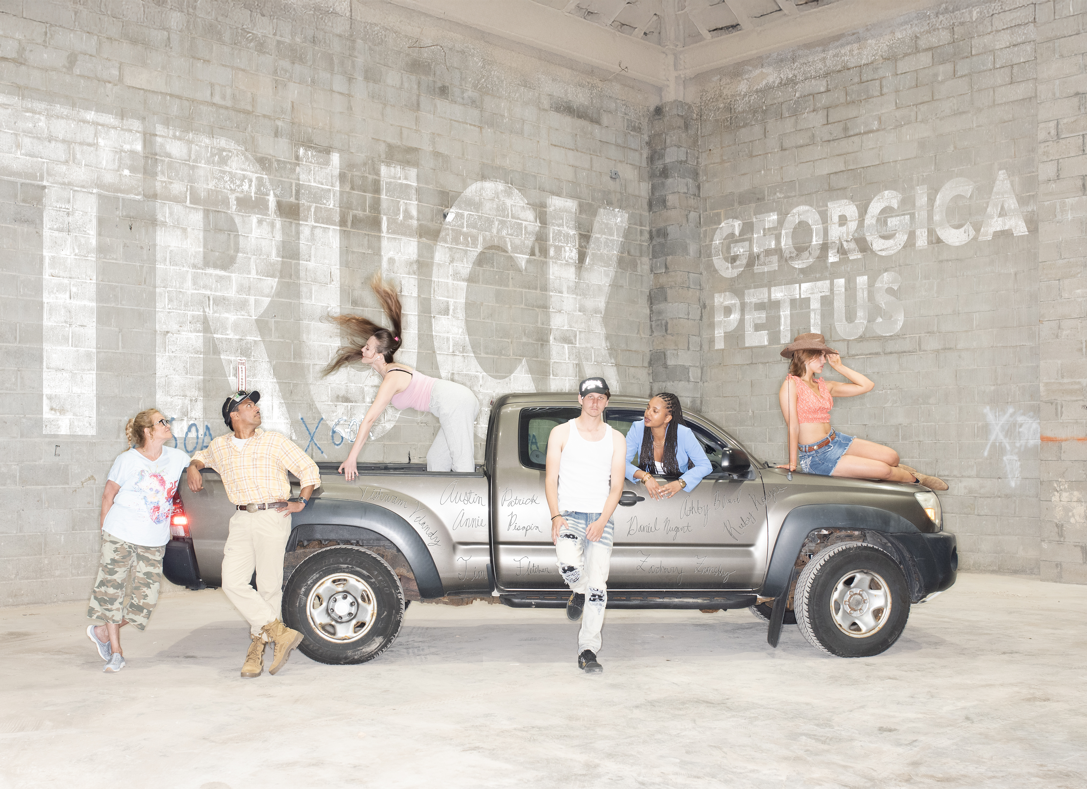 Several people crowd around a grey pickup truck