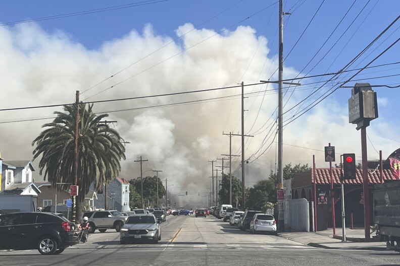 A large plume of smoke spreads across an urban street.