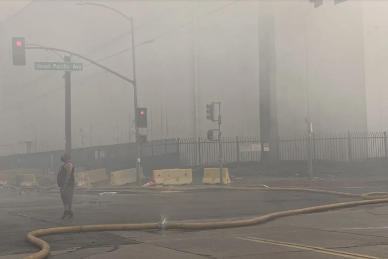 A man stands in the middle of a street filled with haze and smoke.