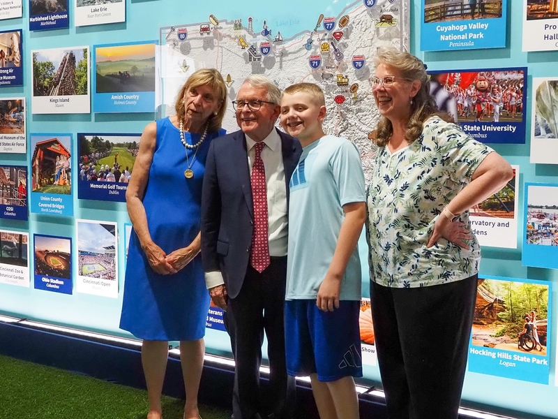 From left, Ohio first lady Fran DeWine and Gov. Mike DeWine take a photo with Miles Armiger, 12, of Severn, Maryland, and his grandmother, Robyn Toman, on Thursday, June 25, 2026, at the Ohio exhibit, part of the Trump administration's Freedom 250 Great American State Fair. (Photo by Ashley Murray/States Newsroom)