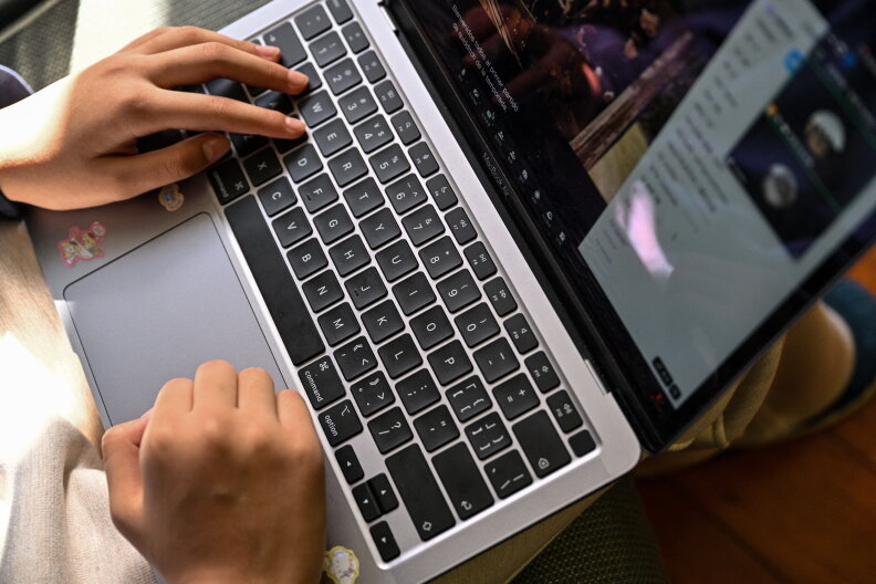 A close up of a person's hands hovering over a laptop keyboard.