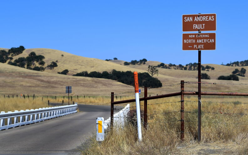 A sign at the San Andreas Fault reads: Now Entering North American Plate. In a field alongside the road.