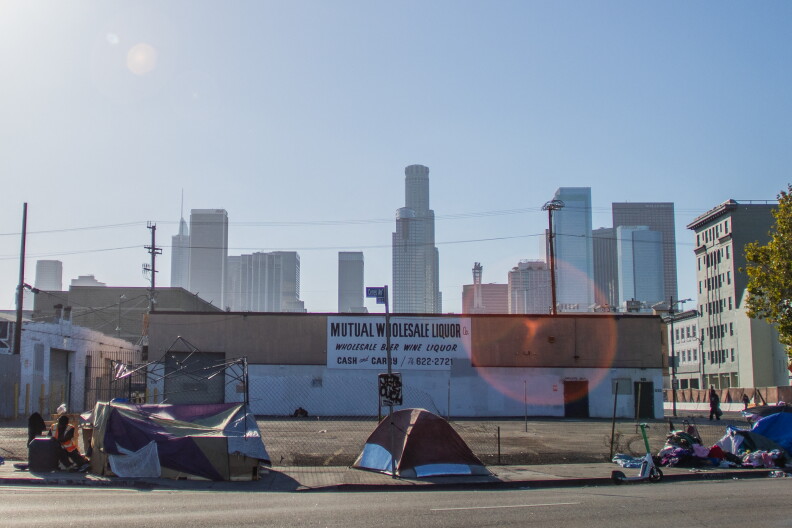 Tents on a sidewalk in front of a downtown skyline