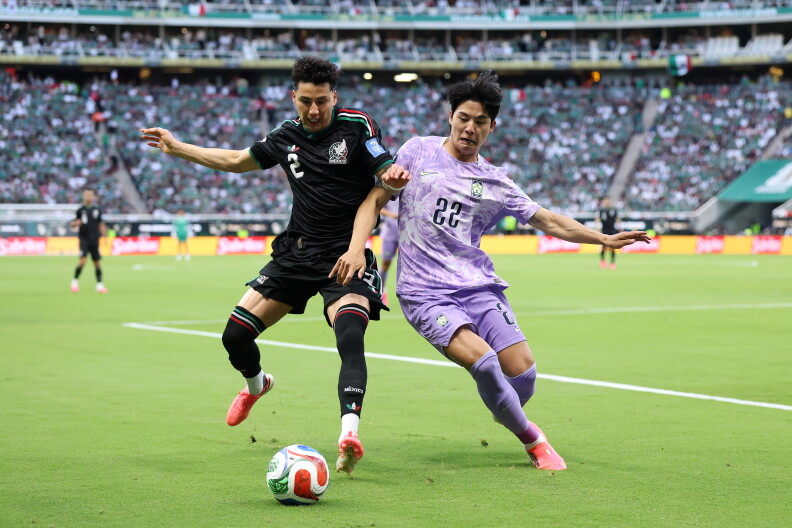 Two men in different uniforms vie for a soccer ball in a stadium.