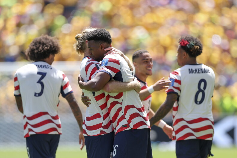 Men in uniform embrace on a soccer field.