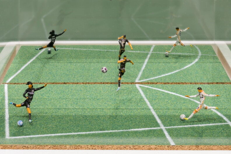 An image of a number of miniature soccer players kicking a football