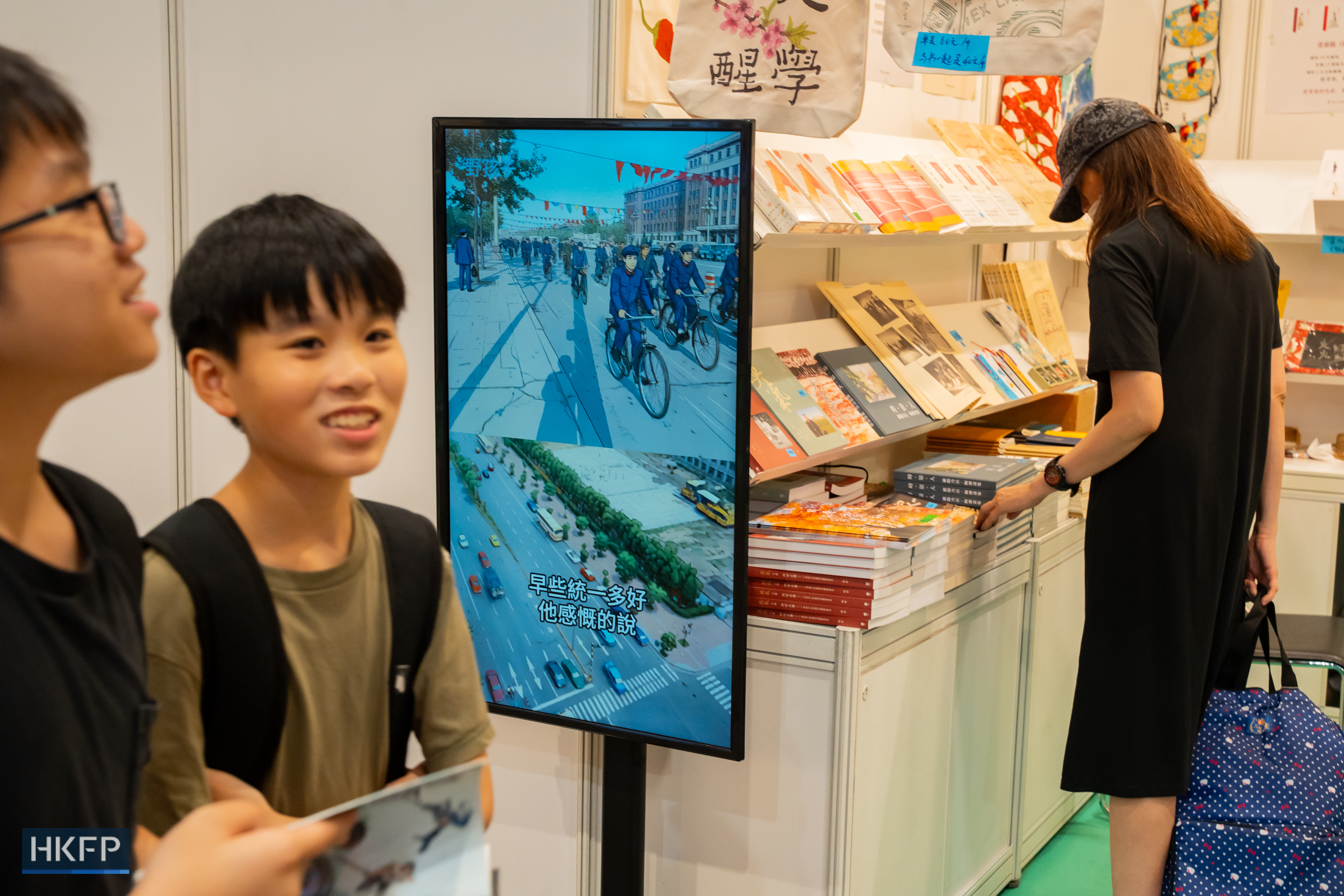 Hong Kong Book Fair in Hong Kong Convention and Exhibition Centre in Wan Chai, on July 17th, 2026. The screen in the photo is showing an animation, with the subtitle reading: "'The earlier the reunification, the better,' he muses." Photo: Kyle Lam/HKFP.
