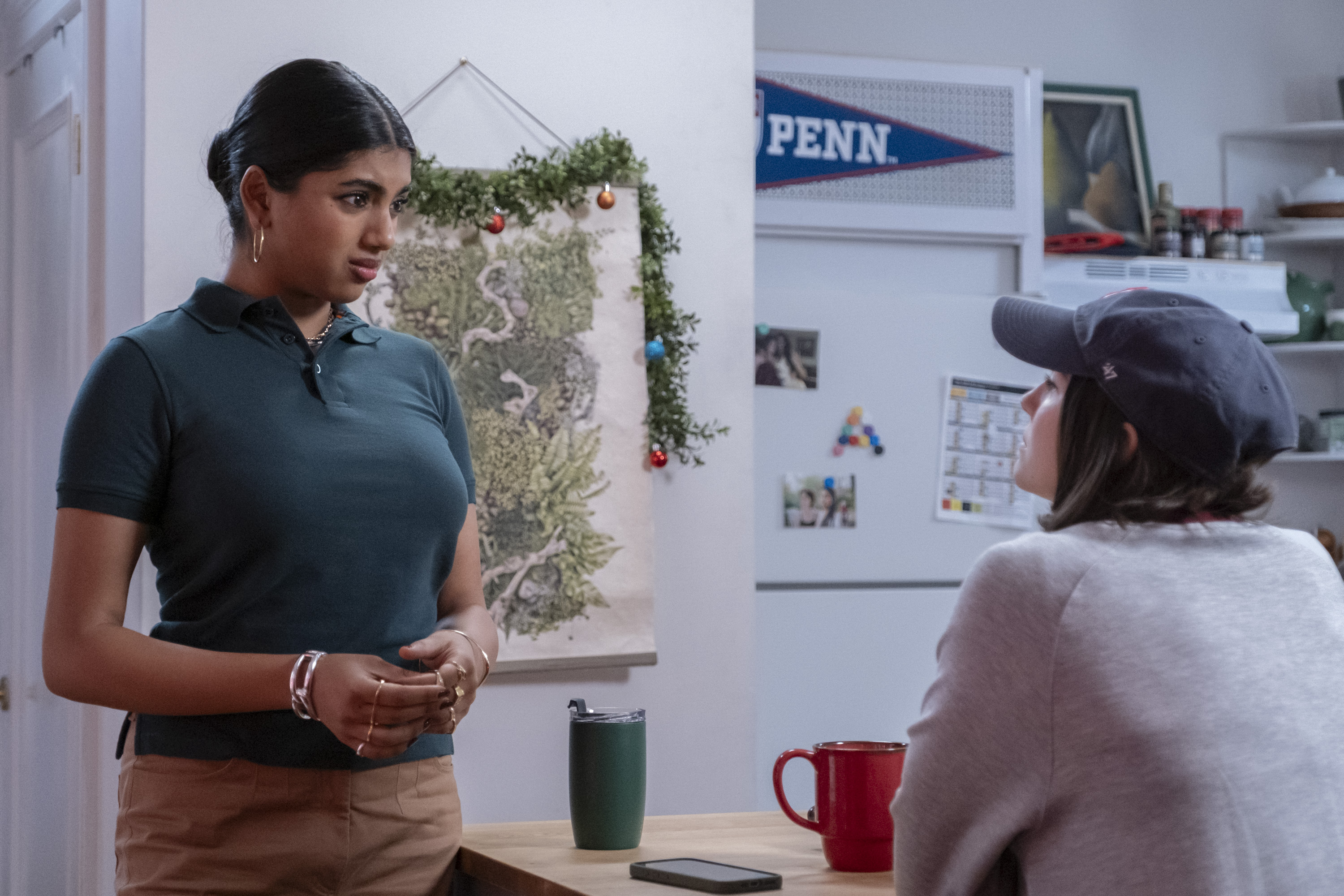 Two characters on a TV show have a discussion at the kitchen table.