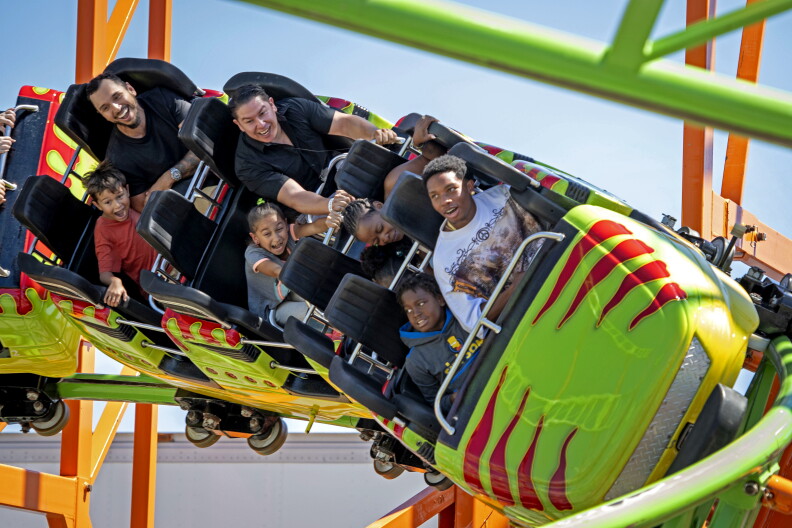 A close-up photo of an amusement park ride β a neon green car is racing along a roller coaster track. Half the people are laughing and smiling and the other half looks like they are screaming for it all to end.