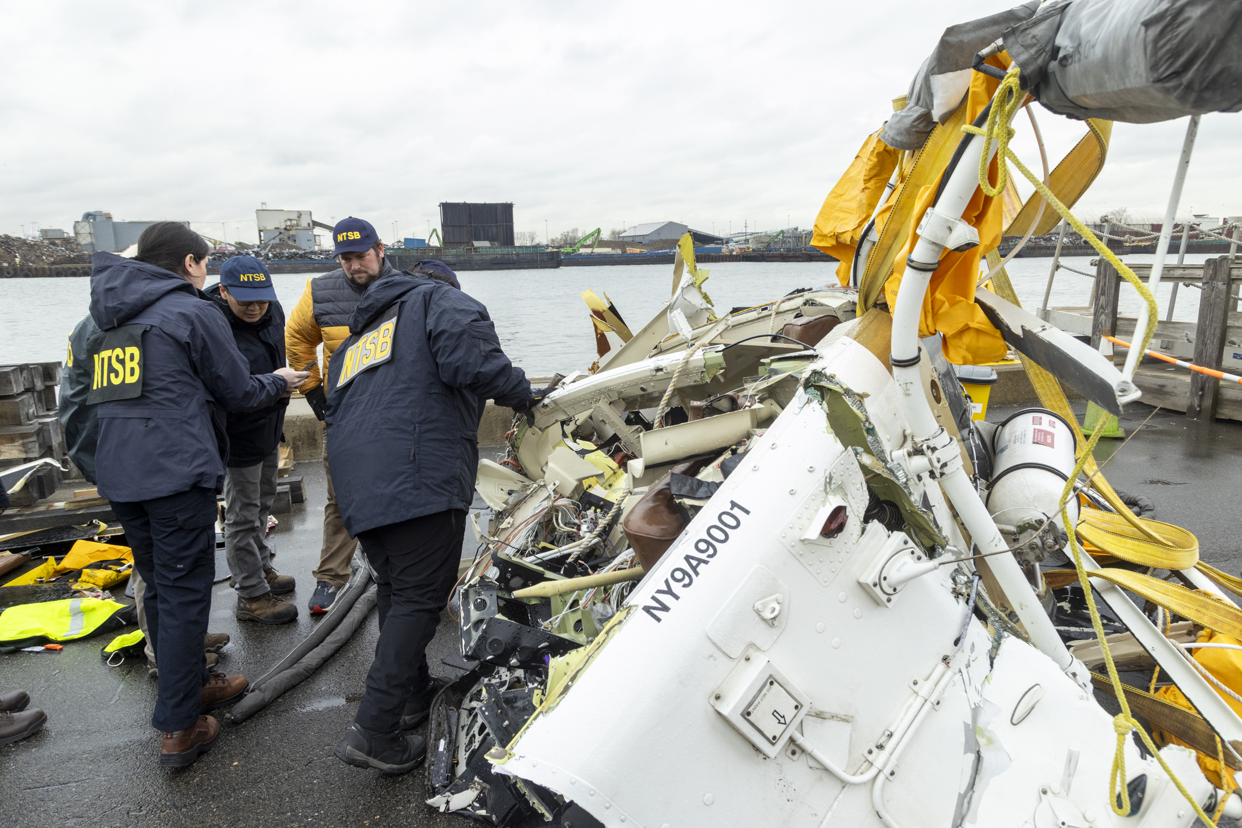 Inspectors view the wreckage of a helicopter.