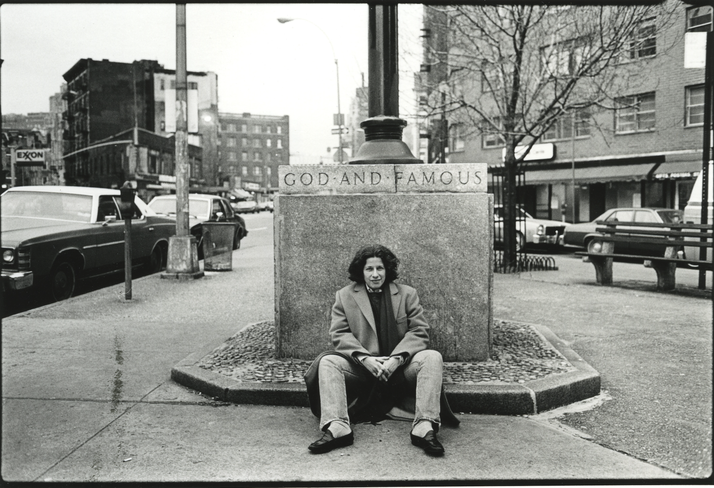 Fran Lebowitz sits on a the street.
