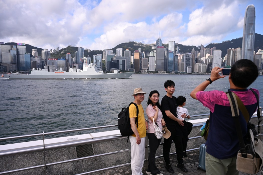 A family poses for photos as the Chinese People's Liberation Army (PLA) Navy guided-missile destroyer Nanning (162) sails through Victoria Harbour during its arrival in Hong Kong for a five-day visit on July 2, 2026. Photo: Peter Parks/AFP.