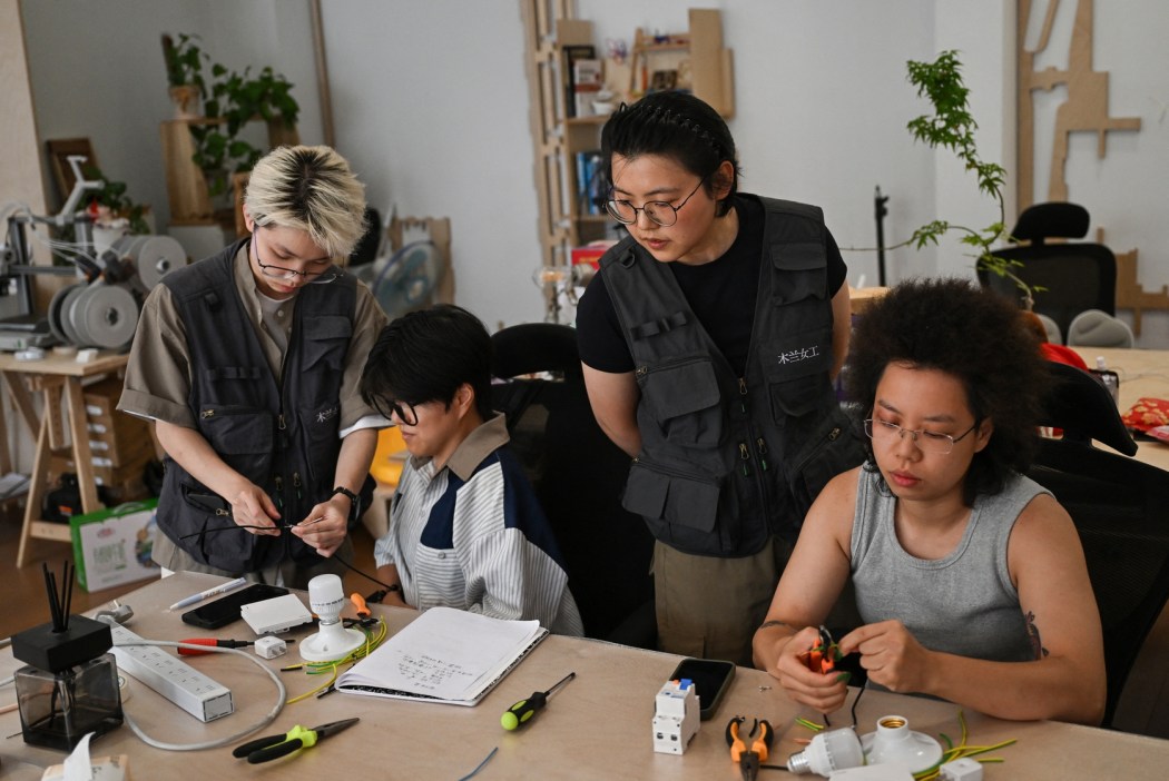 This picture taken on June 28, 2026 shows Wu Shuang (C) and Wang Risun (L) giving an electricity course to a group of women at the Mulan Build workshop in Hangzhou, in eastern China's Zhejiang province.