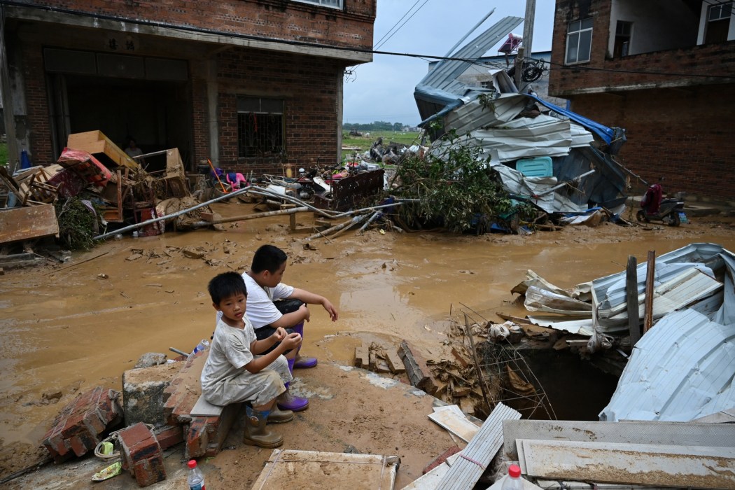 Children sit next to damaged houses in Liulan village, in Hengzhou city, in China's southwest Guangxi region on July 8, 2026. Photo: Greg Baker/AFP.