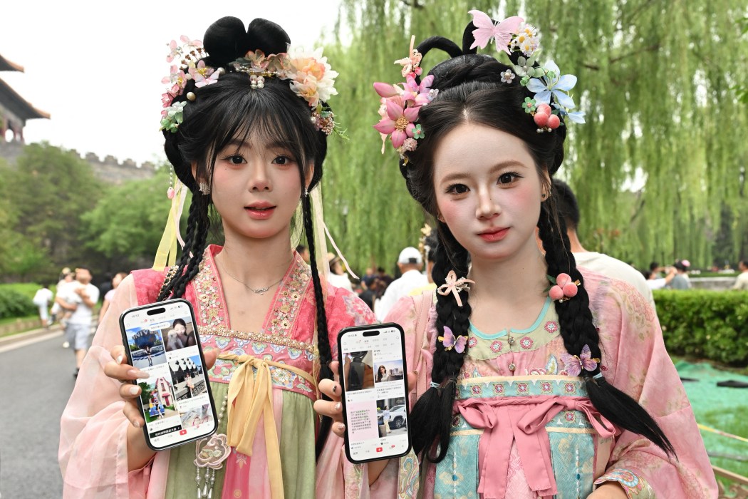 Two tourists from Jilin province show their Xiaohongshu accounts on their mobile phones as they visit the Forbidden City in Beijing on July 11, 2026. Photo: Adek Berry/AFP.