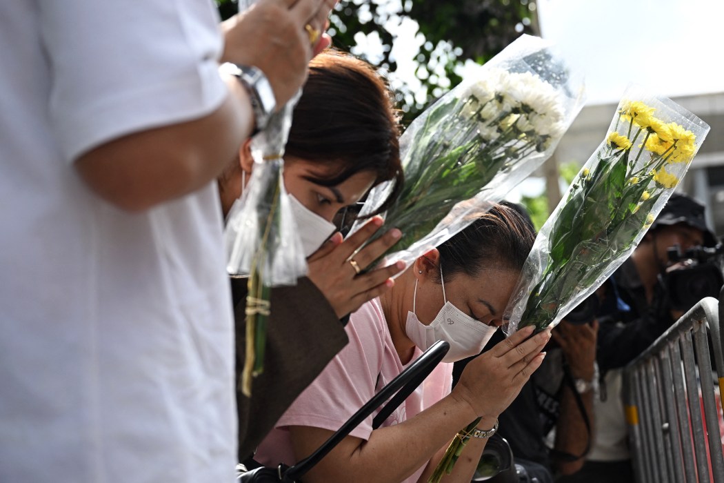 Relatives of a victim of a bar fire pray in front of the Rong Beer Na Lat Phrao bar in Bangkok on July 14, 2026. Photo: Lillian Suwanrumpha/AFP.