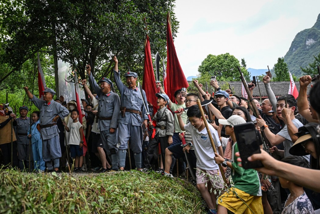 This photo taken on July 25, 2026 shows performers and tourists taking part in a reenactment of a battle between Chinese Communist and Nationalist forces.