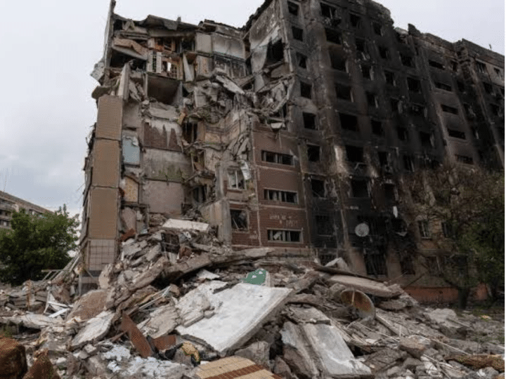 A concrete tower block in Ukraine damaged from an air strike from Russia with scorch marks on the side and rubble piled up on the ground