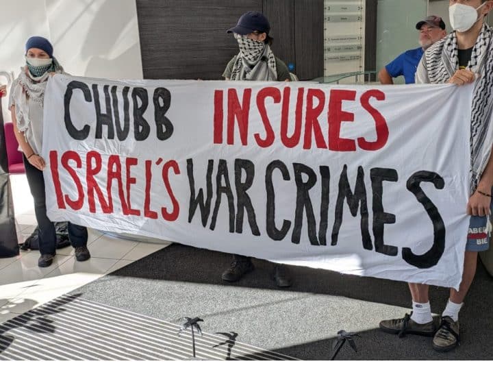 Chubb lobby protesters lod a banner saying Chubb Insures Israel's War Crimes