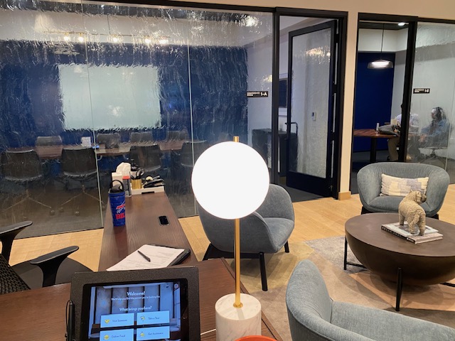 An office space with armchairs, a coffee table and conference rooms with glass windows.