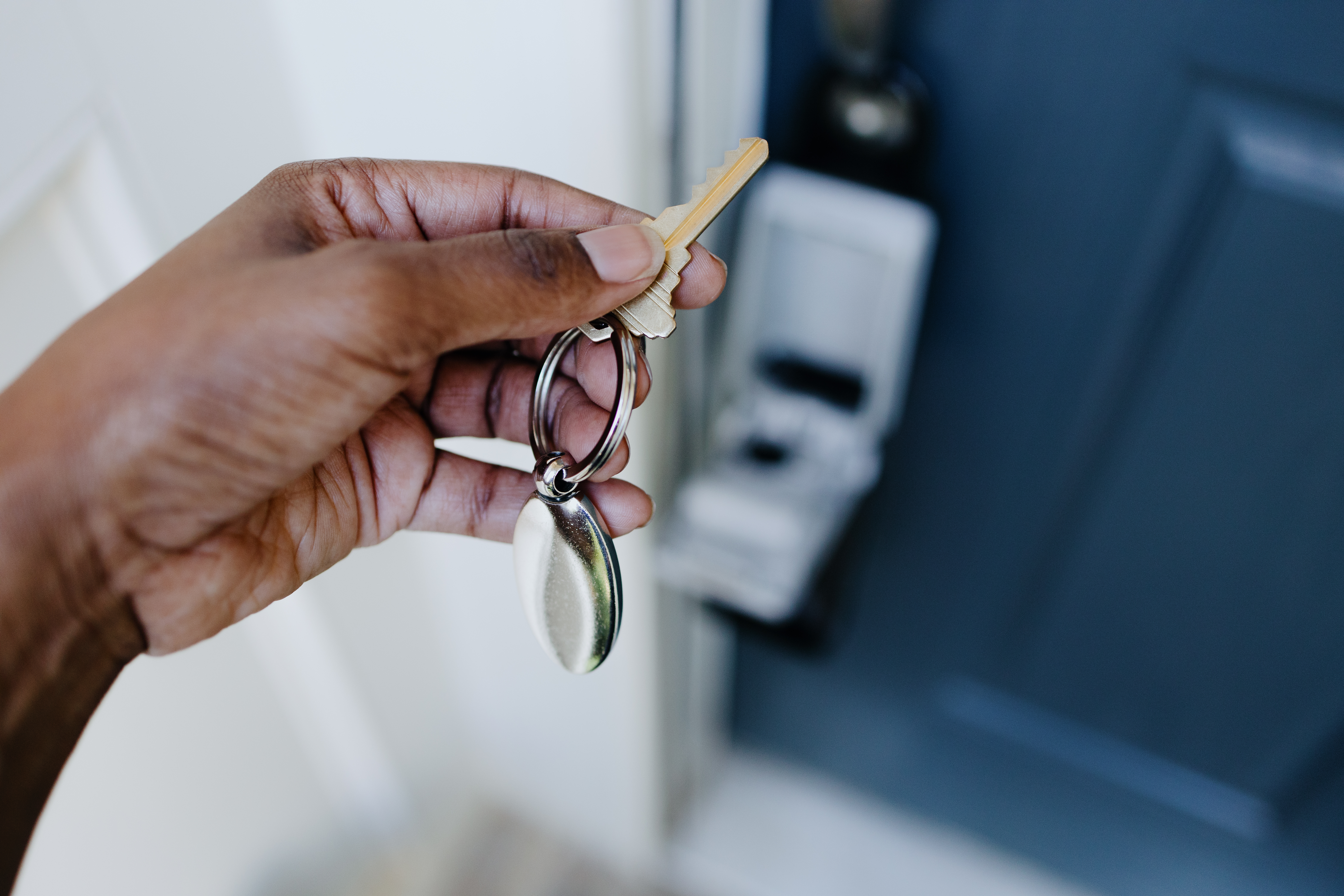 A hand turns a key in a door.