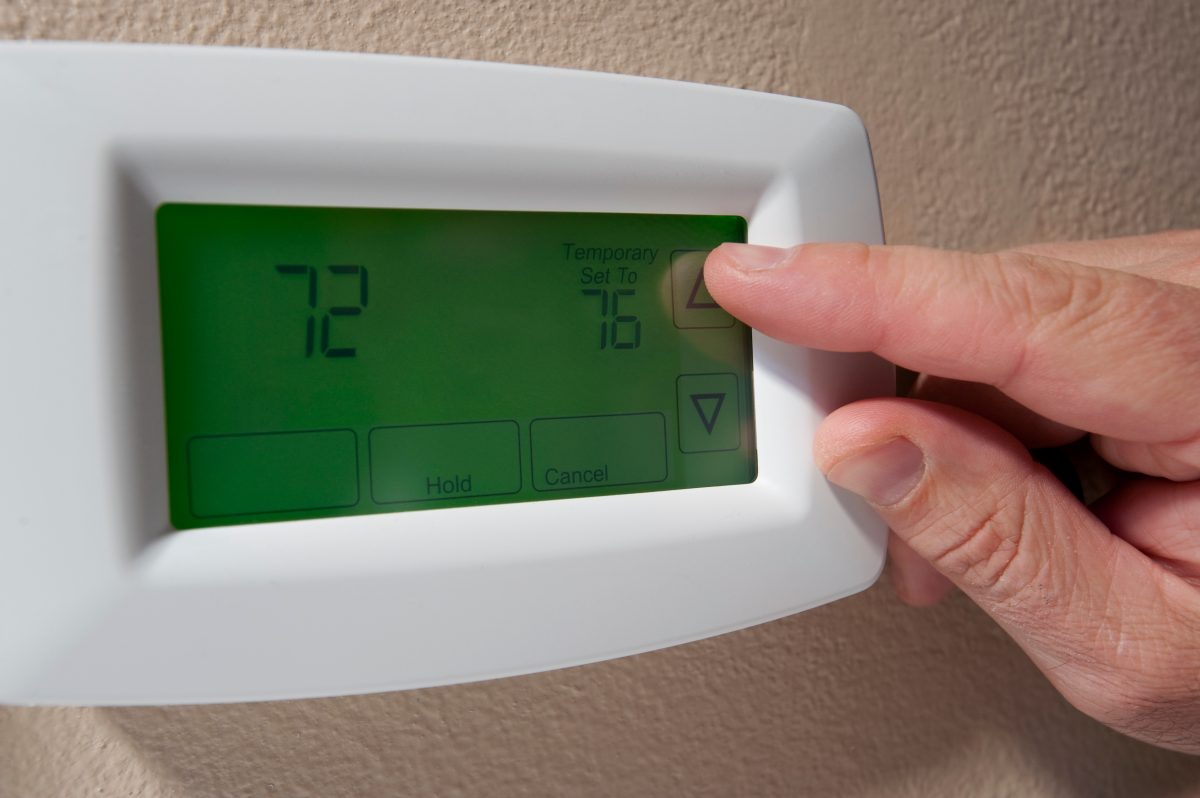 Hand resets the temperature on home thermostat