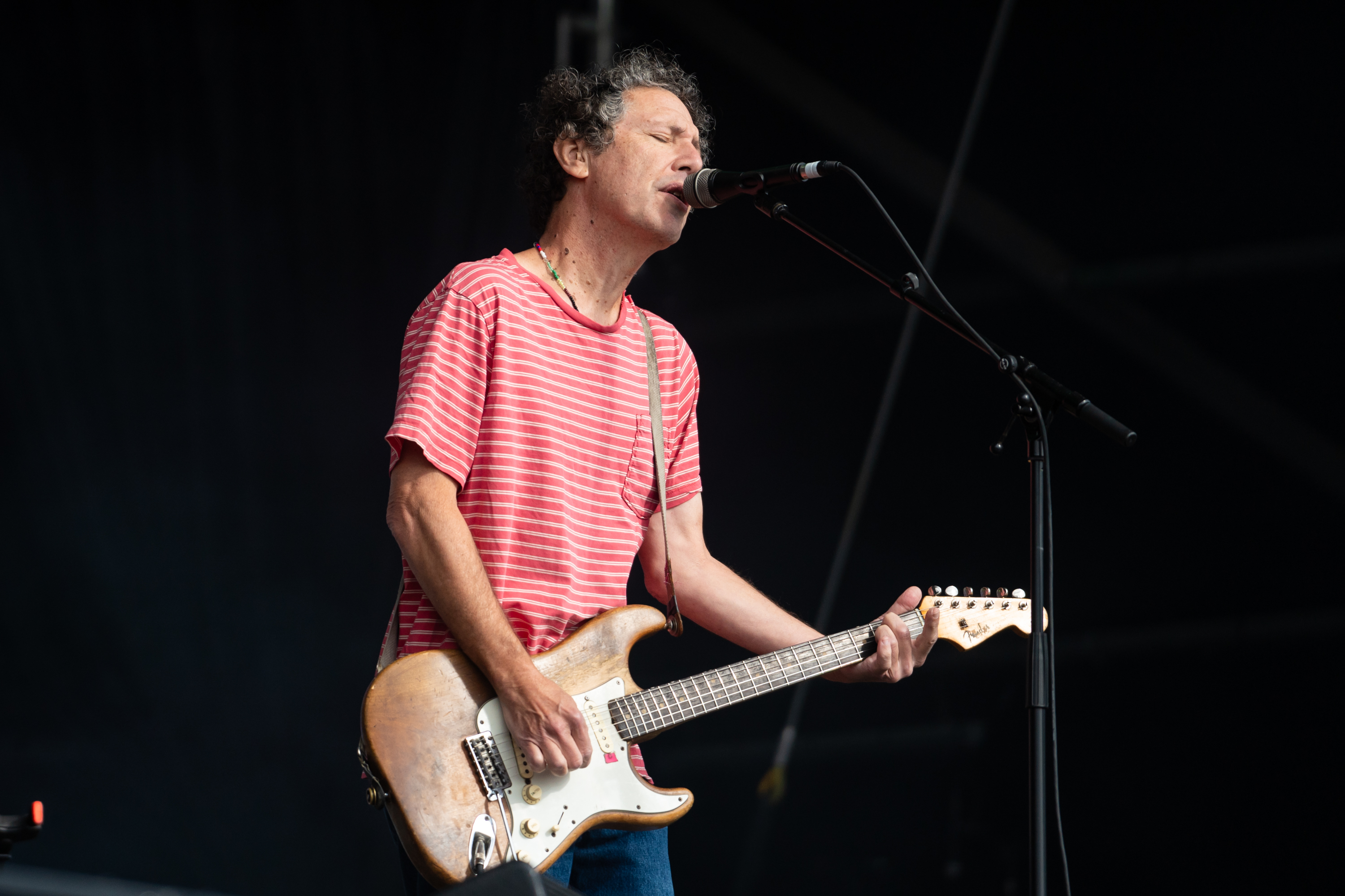 A guitar player sings on a stage.