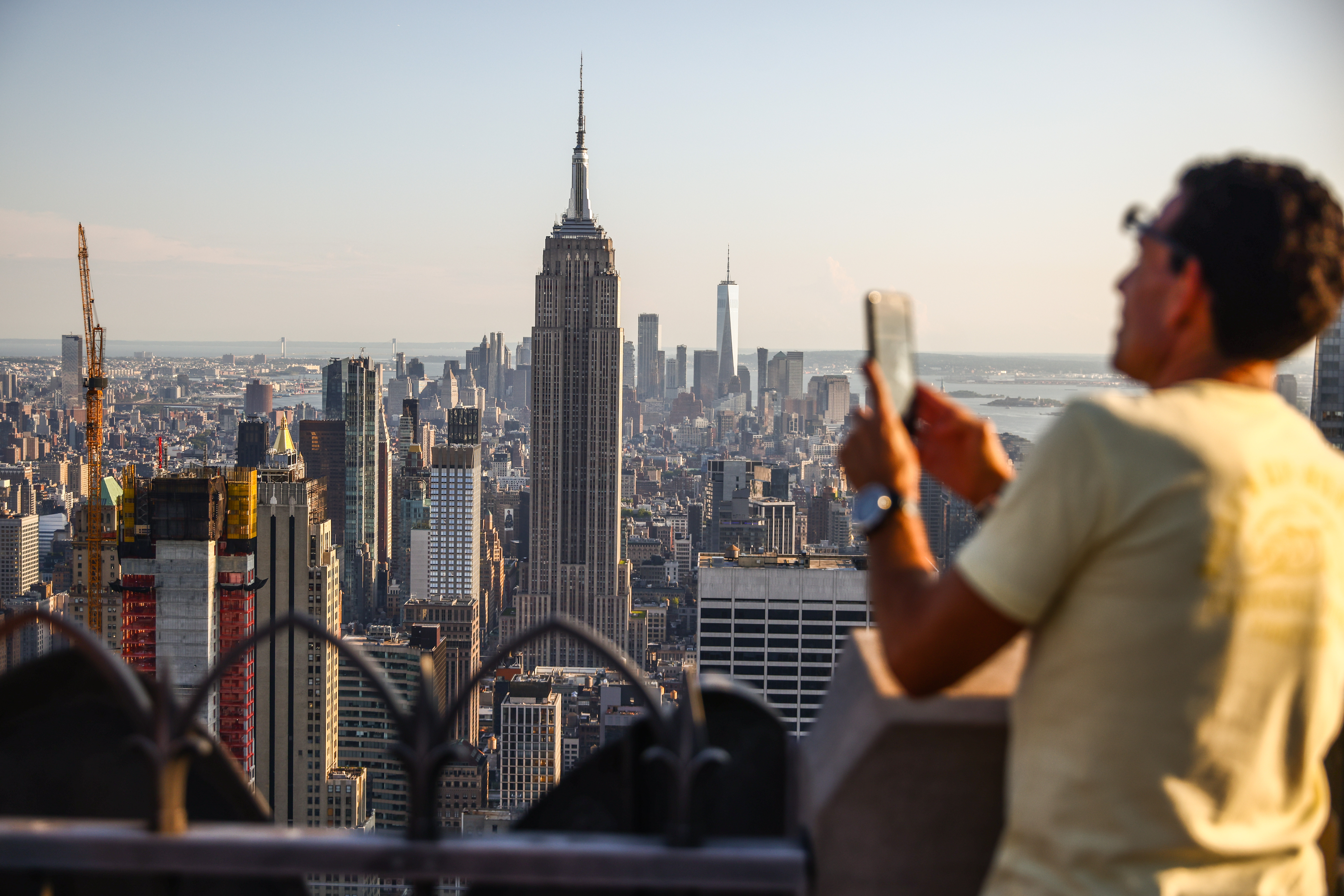The view of Manhattan from a building's roof with a man in the foreground taking a photo