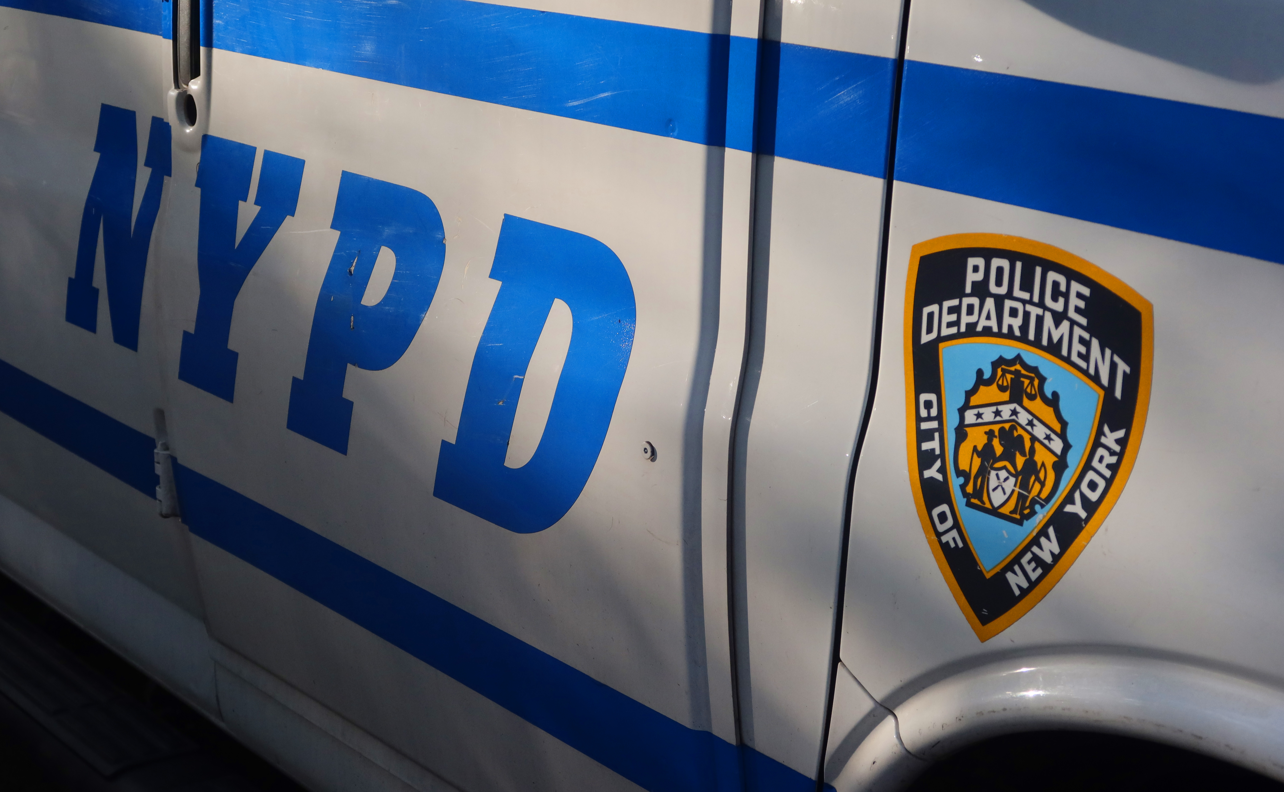 The sun illuminates an NYPD logo on the side of a vehicle outside the First Precinct on April 30, 2025, in New York City.