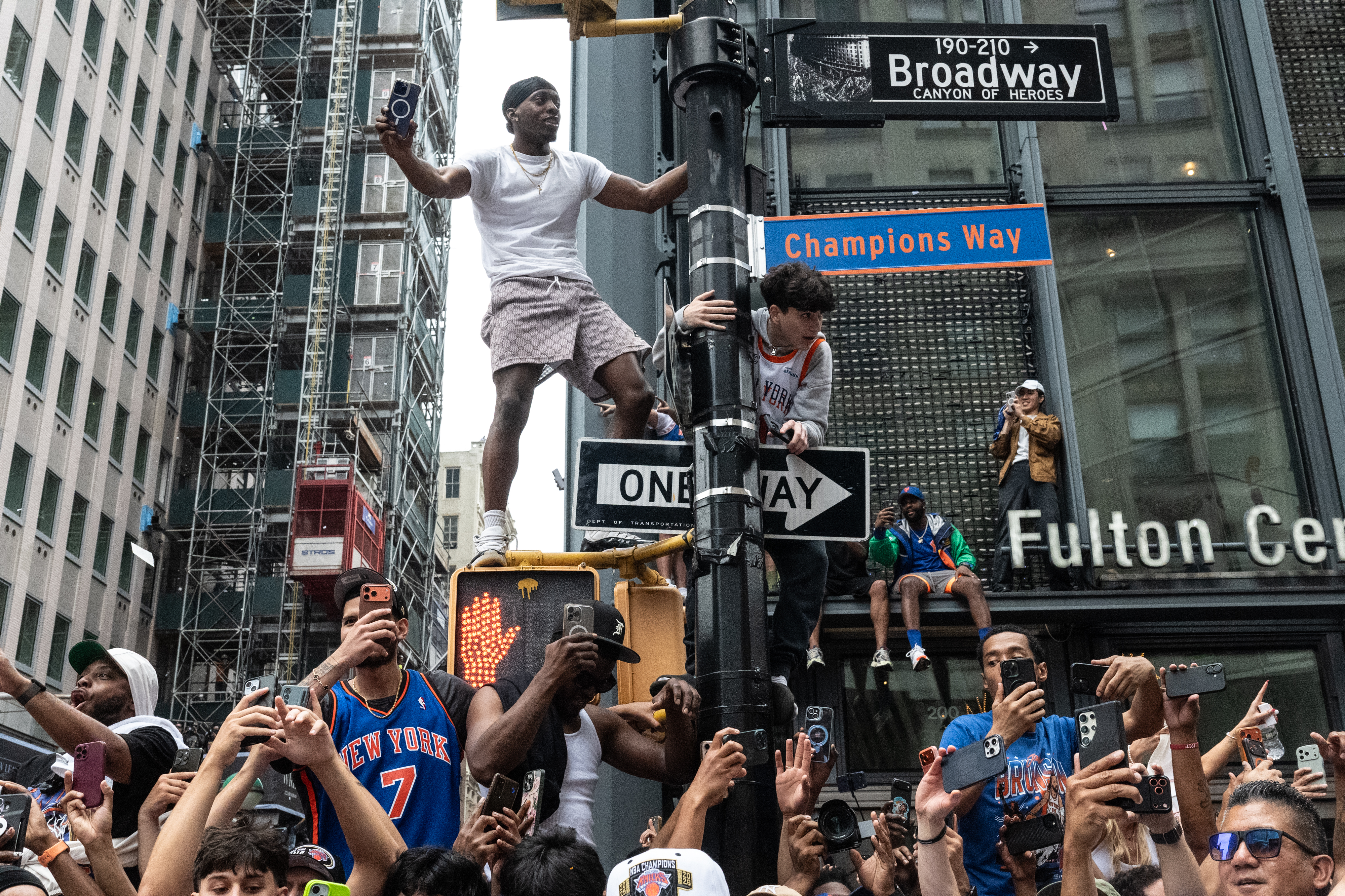 Fans climb a lamp post near a sign renaming Broadway as "Champions Way" during the New York Knicks Championship ticker-tape parade in June.
