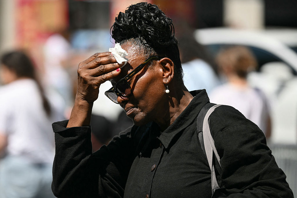A woman wipes sweat from her face as she walks through Midtown Manhattan during a heat wave in New York City on July 3, 2026.