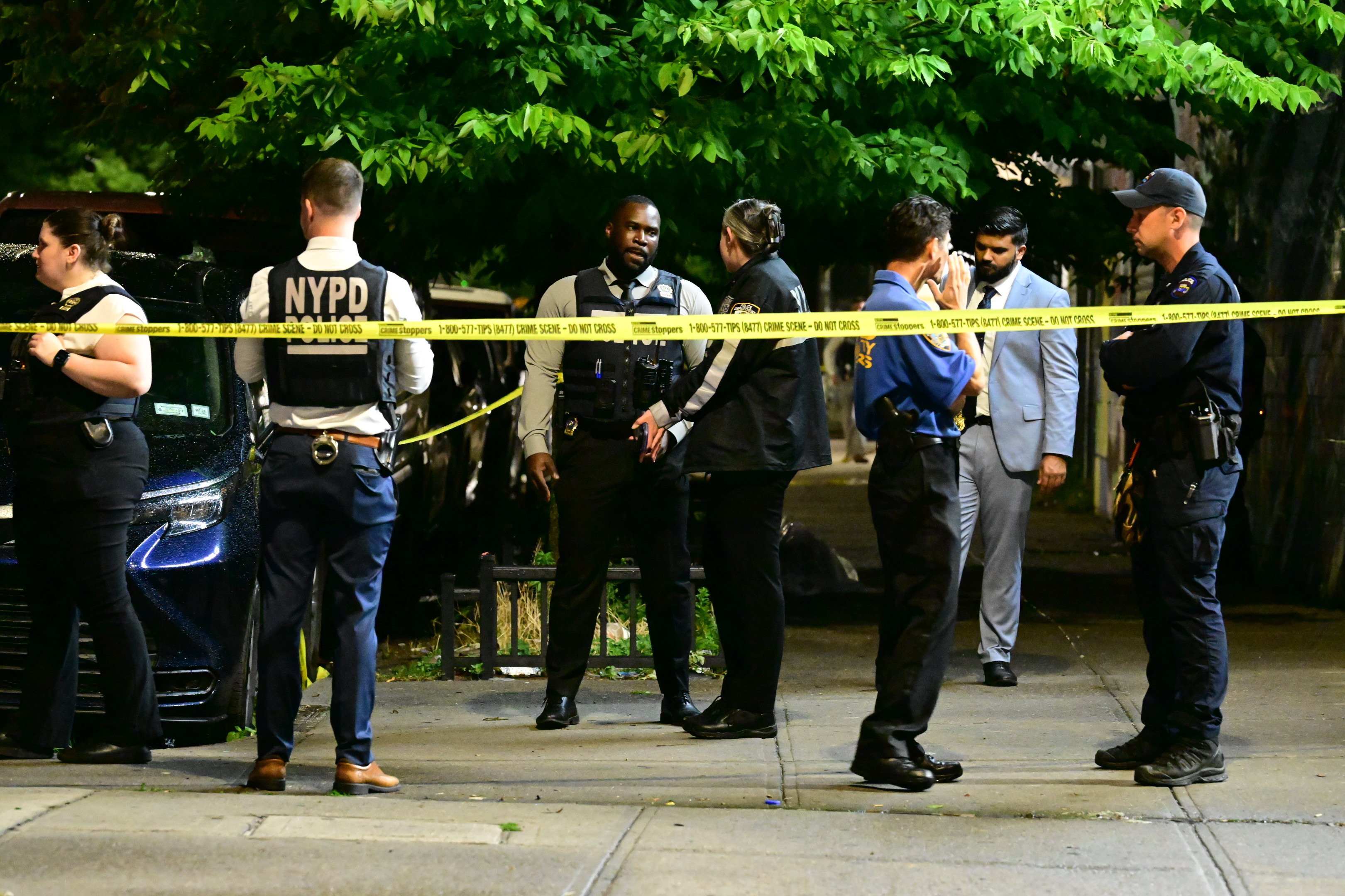 NYPD officers work at the scene after eight people, including four children, were shot in a mass shooting near the intersection of West 30th Street and Surf Avenue in the Coney Island neighborhood of Brooklyn.