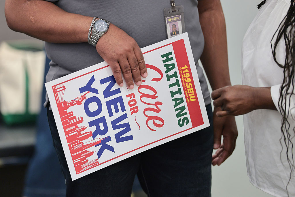 People hold signs during a press conference on the end of the Temporary Protected Status at the 199SEIU Headquarters on July 10, 2026, in New York City.