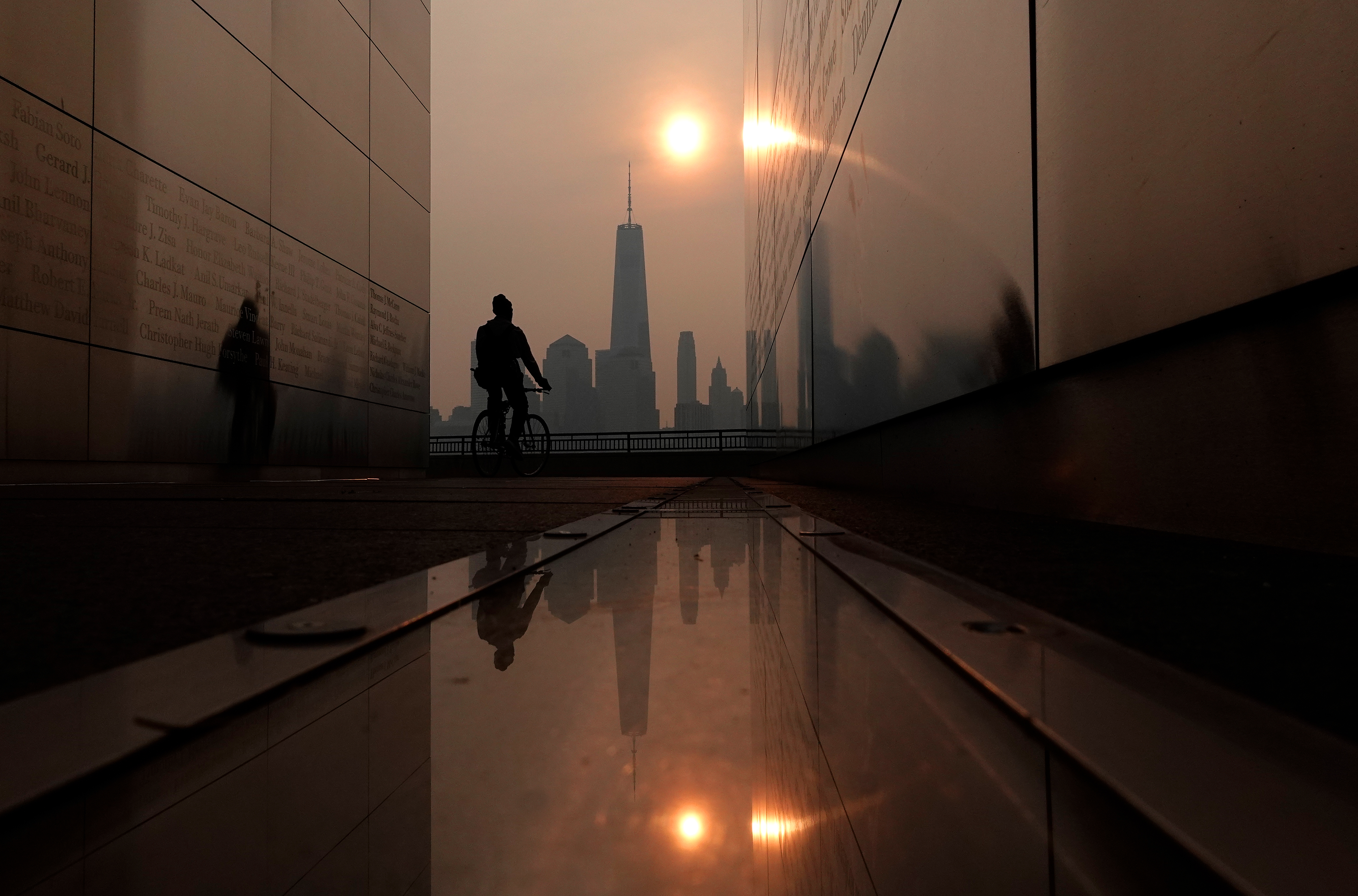 Wildfire smoke from Canada shrouds the sun as it rises behind the skyline of lower Manhattan and One World Trade Center in New York City.