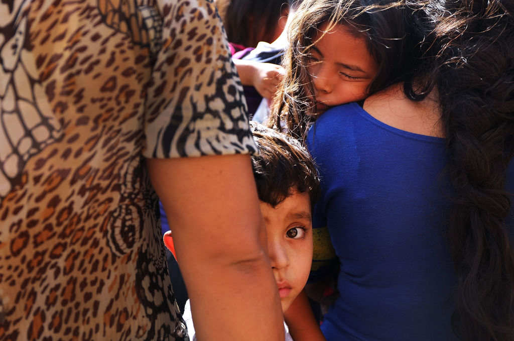 Dozens of women, men and their children, many fleeing poverty and violence in Honduras, Guatamala and El Salvador, arrive at a bus station following release from Customs and Border Protection on June 23, 2018, in McAllen, Texas.