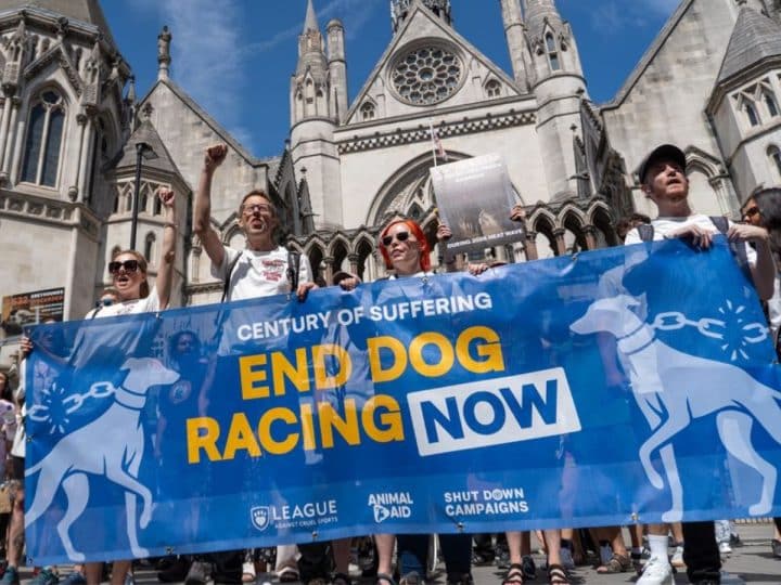 Protesters against greyhound racing hold a banner saying End Dog Racing Now