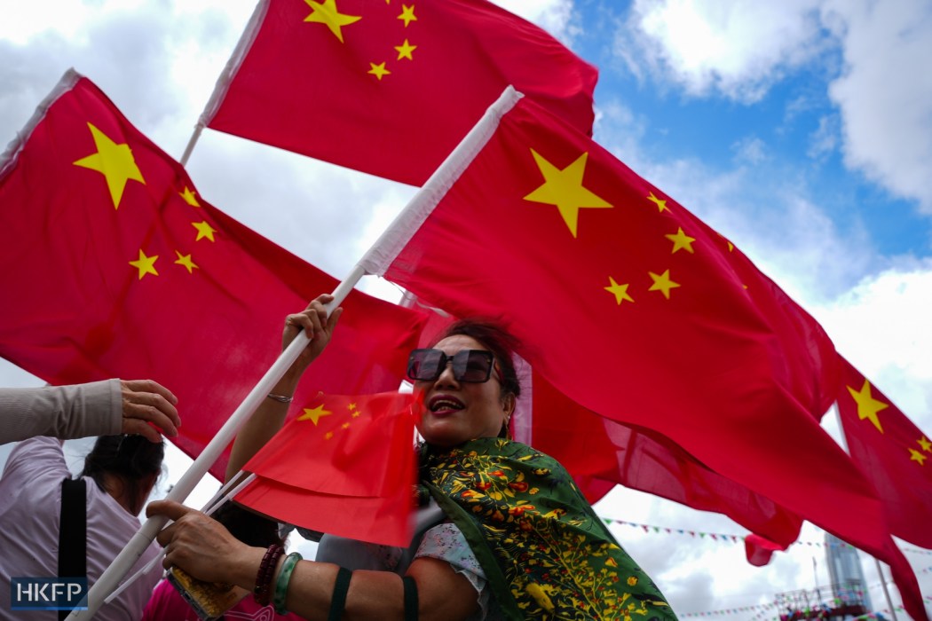 People wave China's national flag on July 1, 2025 in Tsim Sha Tsui, Hong Kong. Photo: Kyle Lam/HKFP.
