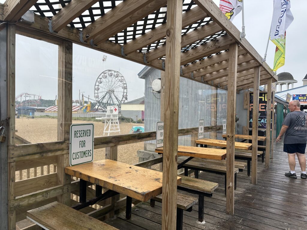 Empty tables line the pier at Old Orchard Beach, Maine, where a drop in Canadian visitors has affected business. Nationally, leisure and hospitality jobs dipped 61,000 in June, reflecting slower seasonal hiring. (Photo by Kevin Hardy/Stateline)