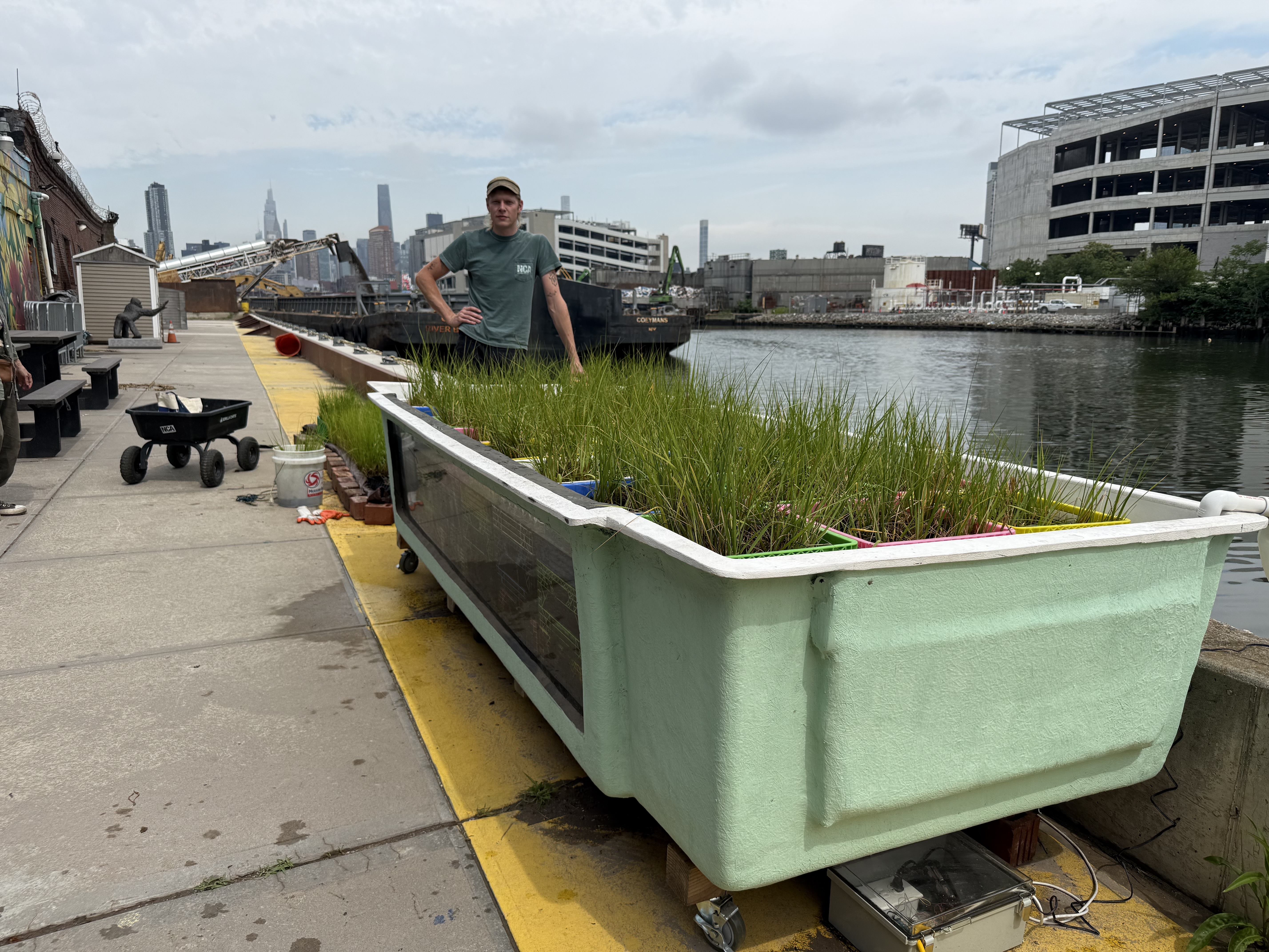 Gus Perry, restoration and marine projects coordinator for the Newtown Creek Alliance poses with TINA, a 600-gallon tank filled mussels.